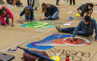 5 people drawing with chalk on a sidewalk